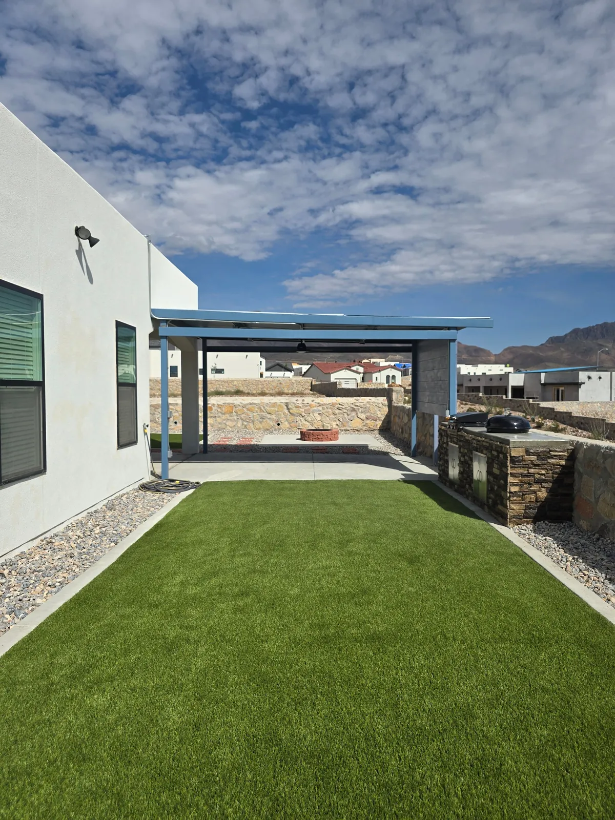 Artificial turf lawn meeting a shaded concrete patio in a finished backyard